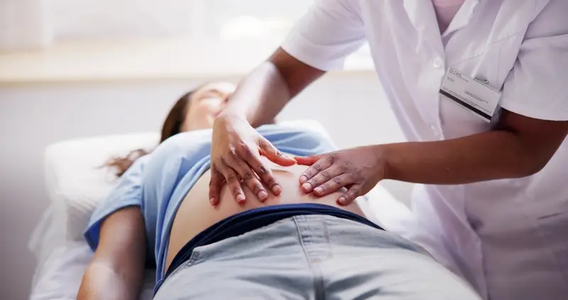 a massage therapist applies pressure to points of the abdomen, as part of tcm prenatal massage